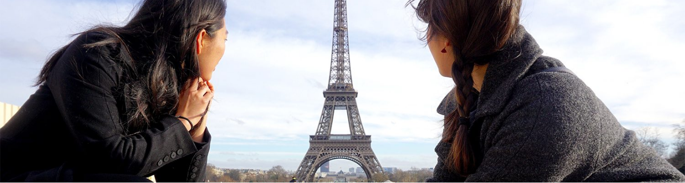 two people facing the Eiffel Tower in the background 